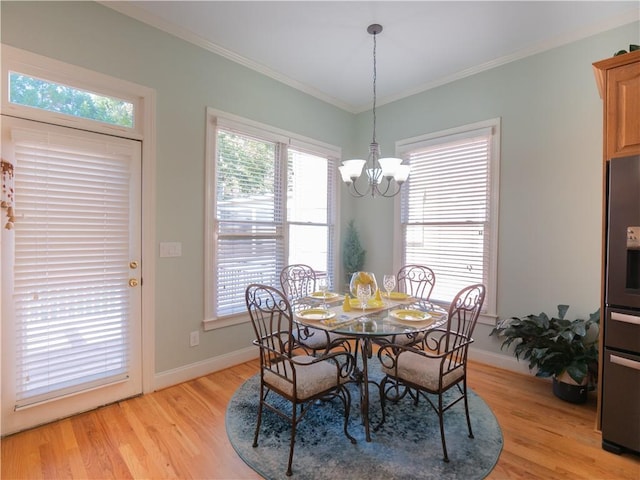 dining area with ornamental molding, a notable chandelier, and light hardwood / wood-style floors