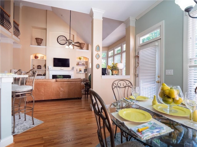 dining area with hardwood / wood-style flooring, ornamental molding, vaulted ceiling, built in features, and ceiling fan