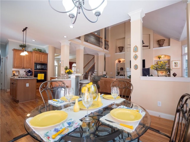 dining room with a chandelier, ornate columns, built in features, light hardwood / wood-style floors, and crown molding