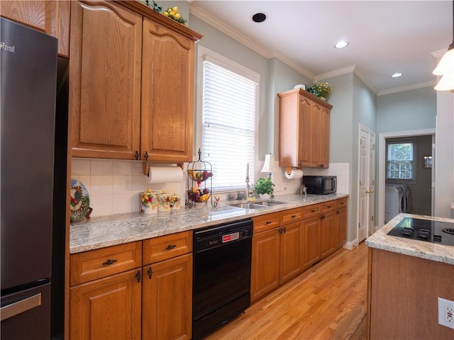 kitchen featuring light stone countertops, light hardwood / wood-style flooring, black appliances, crown molding, and sink