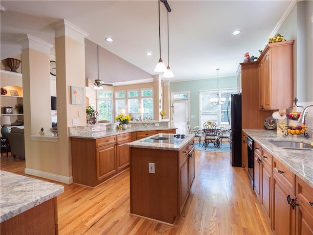 kitchen with hanging light fixtures, sink, plenty of natural light, and a kitchen island with sink