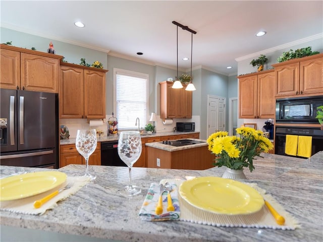 kitchen featuring a kitchen island, black appliances, pendant lighting, crown molding, and light stone counters