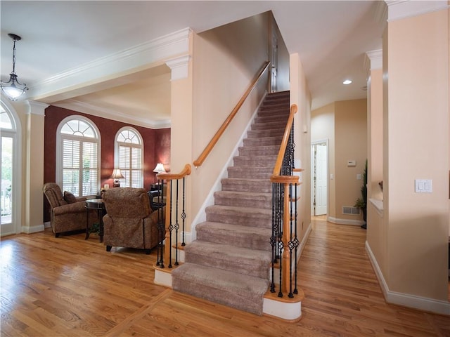 stairway with ornamental molding and wood-type flooring