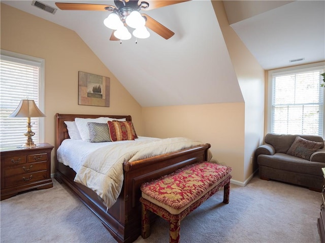 bedroom featuring ceiling fan, vaulted ceiling, multiple windows, and light colored carpet