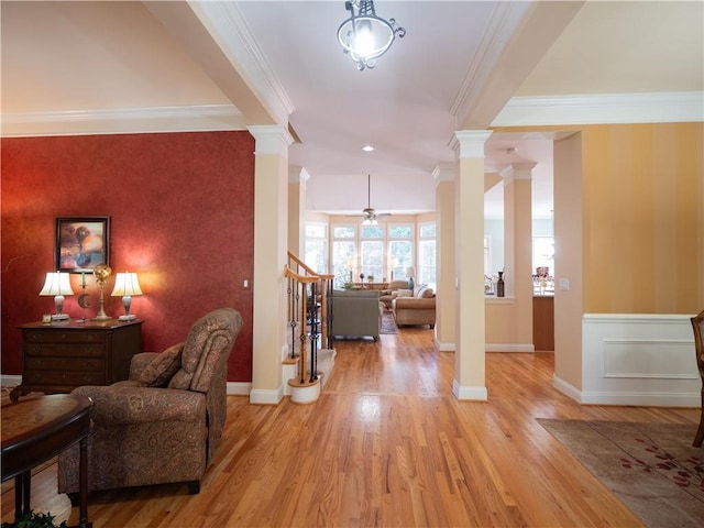 foyer entrance with lofted ceiling, crown molding, decorative columns, light hardwood / wood-style floors, and ceiling fan