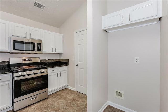 kitchen featuring visible vents, appliances with stainless steel finishes, white cabinets, dark stone countertops, and baseboards