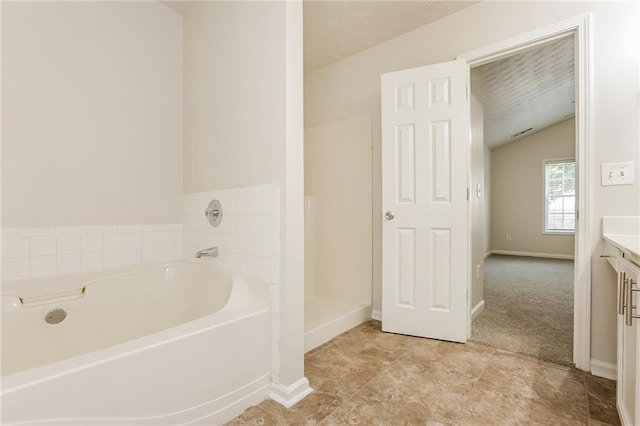 full bath with lofted ceiling, a garden tub, baseboards, and vanity