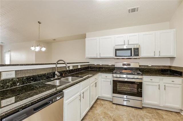 kitchen featuring visible vents, white cabinets, dark stone countertops, stainless steel appliances, and a sink