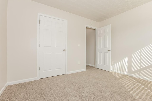 unfurnished bedroom with carpet, a textured ceiling, and baseboards