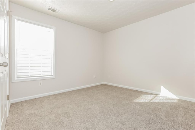 carpeted empty room with baseboards, visible vents, and a textured ceiling