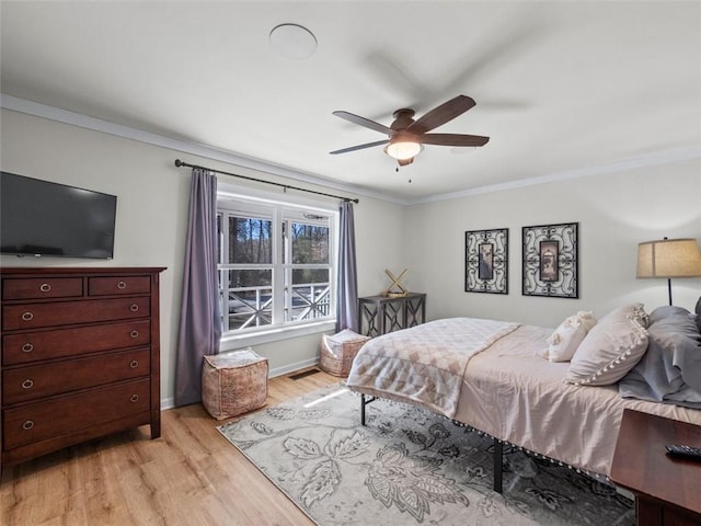 bedroom with light hardwood / wood-style flooring, ornamental molding, and ceiling fan