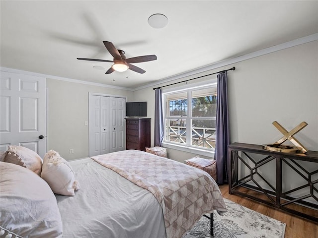 bedroom with crown molding, ceiling fan, hardwood / wood-style floors, and a closet