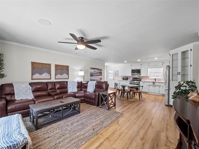 living room with ornamental molding, ceiling fan, and light wood-type flooring