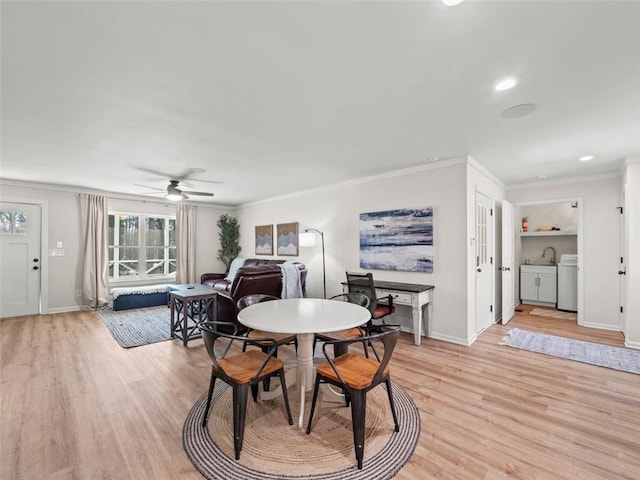 dining room with crown molding, sink, washing machine and clothes dryer, and light hardwood / wood-style floors