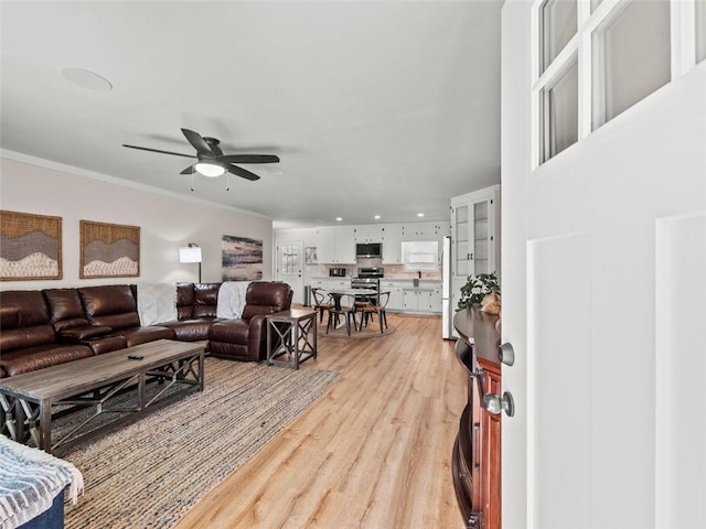 living room with crown molding, ceiling fan, and light hardwood / wood-style floors