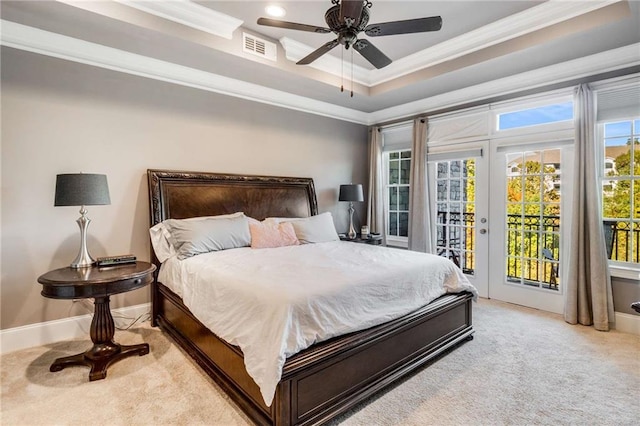 carpeted bedroom with access to exterior, ceiling fan, multiple windows, and a tray ceiling