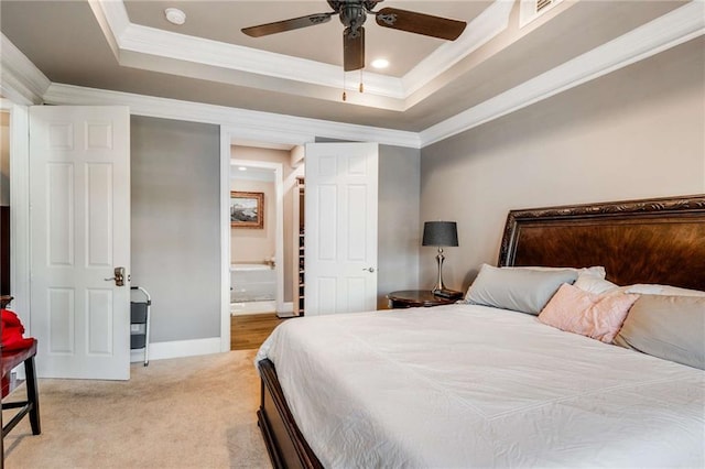 bedroom with connected bathroom, ceiling fan, a tray ceiling, ornamental molding, and carpet