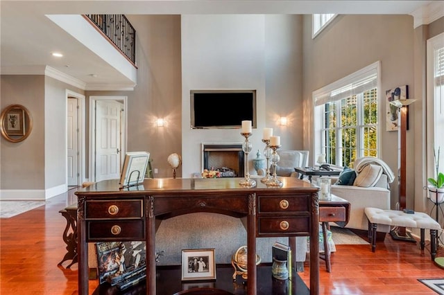 living room with a high ceiling, light wood-type flooring, and ornamental molding