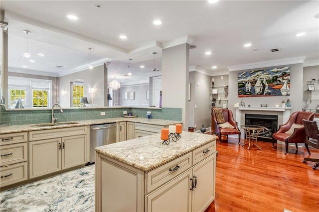 kitchen with sink, stainless steel dishwasher, cream cabinetry, and light hardwood / wood-style flooring