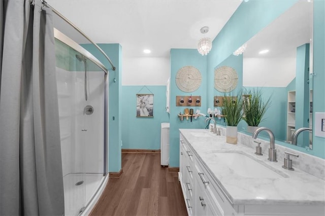 bathroom featuring a sink, wood finished floors, a stall shower, and double vanity