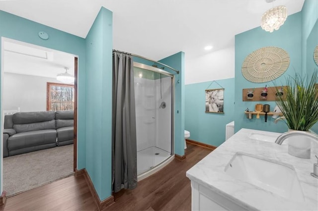 full bath featuring a shower stall, wood finished floors, double vanity, and a sink