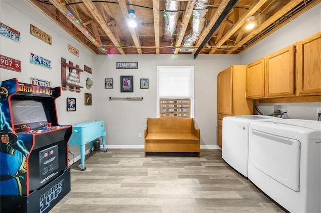 washroom with cabinet space, baseboards, light wood finished floors, and washing machine and clothes dryer