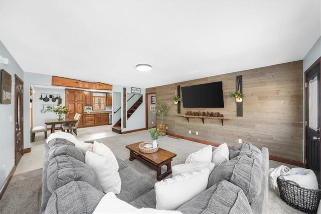 living area with stairs, wooden walls, baseboards, and an accent wall