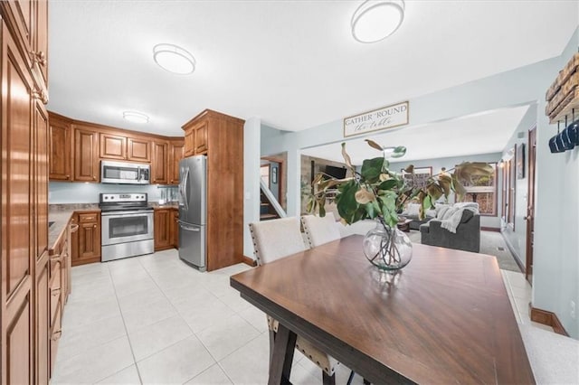 kitchen featuring light tile patterned floors, stainless steel appliances, and brown cabinets