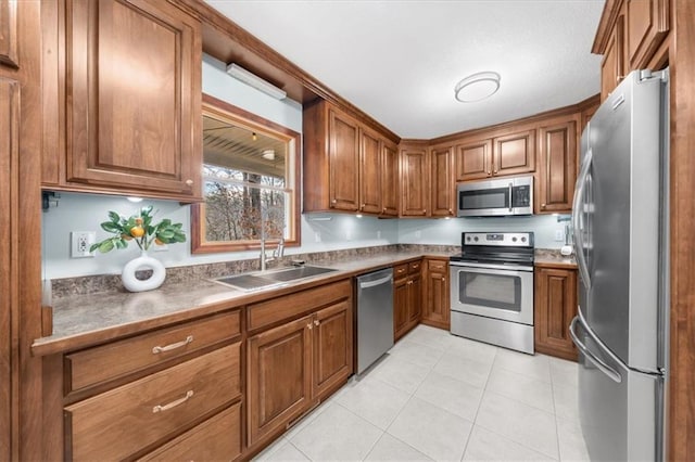 kitchen with light tile patterned floors, brown cabinets, appliances with stainless steel finishes, and a sink