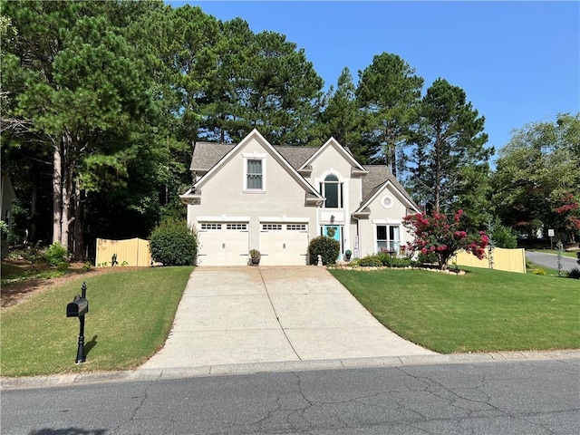 traditional-style home featuring stucco siding, concrete driveway, a front yard, and fence