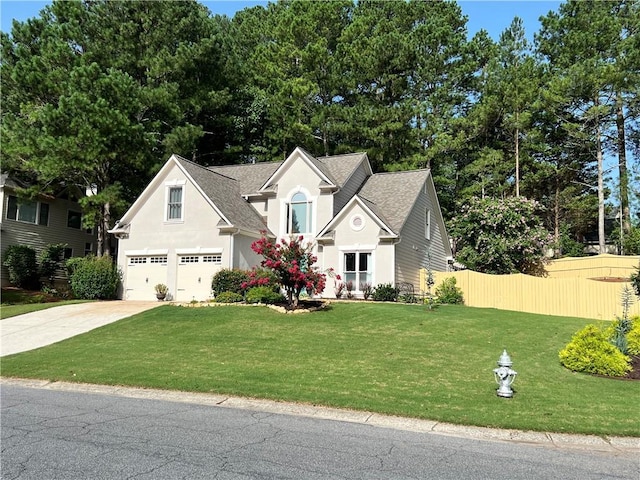 view of front of house with stucco siding, fence, concrete driveway, a front yard, and a shingled roof