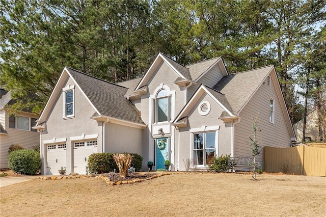 traditional home featuring stucco siding, fence, concrete driveway, a shingled roof, and a garage