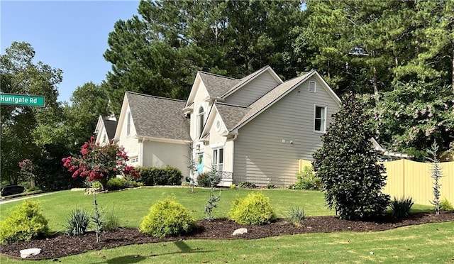 view of home's exterior with a lawn, fence, and roof with shingles