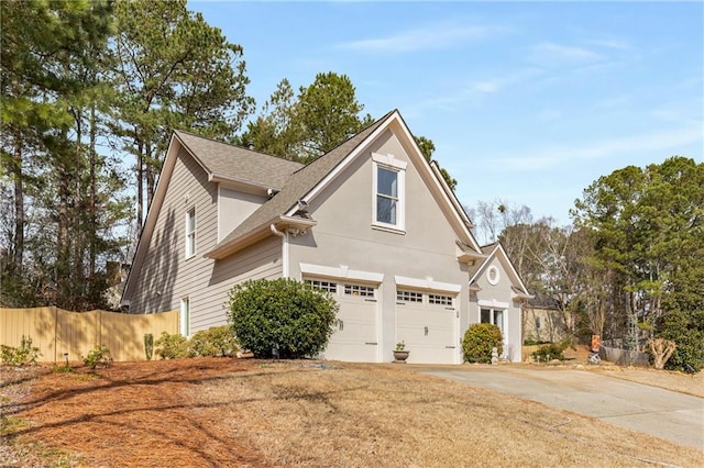 view of home's exterior with an attached garage, a shingled roof, driveway, and fence