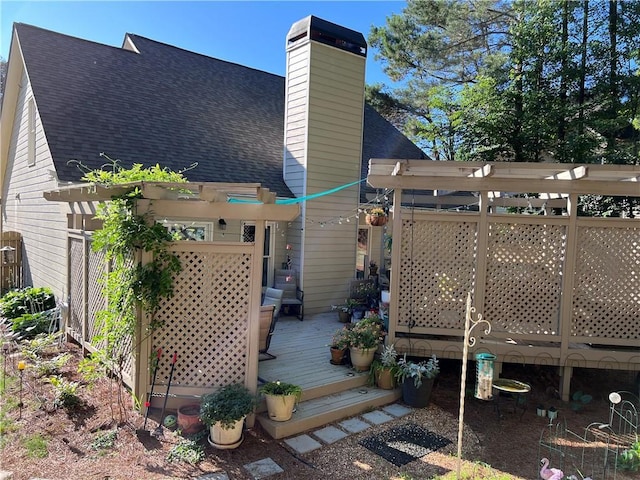 back of house featuring a pergola, a chimney, roof with shingles, and a wooden deck