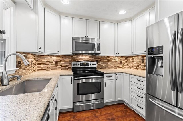 kitchen with appliances with stainless steel finishes, a sink, white cabinetry, backsplash, and recessed lighting