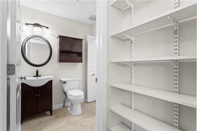 bathroom featuring vanity, toilet, and baseboards