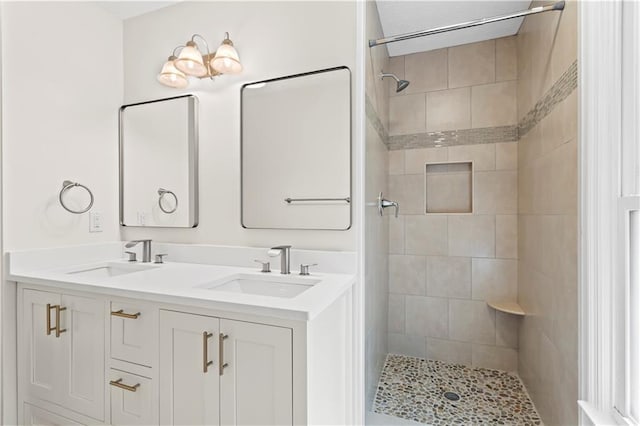full bath featuring tiled shower and double vanity