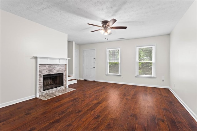 unfurnished living room with ceiling fan, baseboards, hardwood / wood-style flooring, a tile fireplace, and a textured ceiling