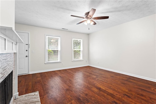 unfurnished living room featuring ceiling fan, wood finished floors, baseboards, a fireplace, and a textured ceiling