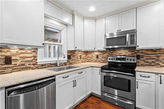 kitchen featuring stainless steel appliances, a sink, white cabinets, and dark wood-type flooring