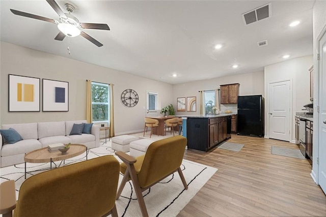 living room with light wood-type flooring, ceiling fan, and sink