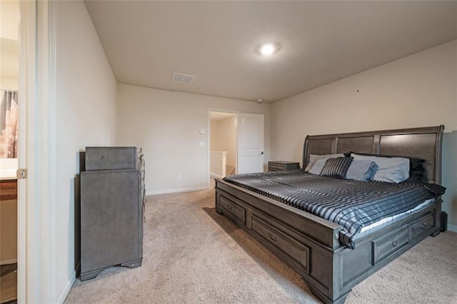 bedroom with connected bathroom and light colored carpet