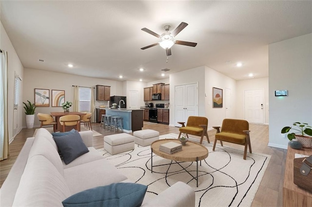 living room with light hardwood / wood-style flooring and ceiling fan