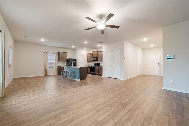 unfurnished living room with ceiling fan, sink, and light hardwood / wood-style flooring