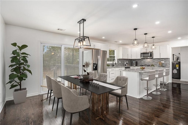 dining room with recessed lighting, a healthy amount of sunlight, dark wood-type flooring, and baseboards