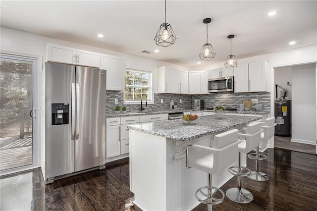 kitchen with a kitchen island, a sink, stainless steel appliances, dark wood-type flooring, and white cabinetry