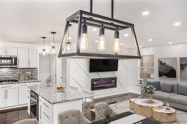 interior space featuring decorative backsplash, open floor plan, white cabinetry, and stainless steel appliances