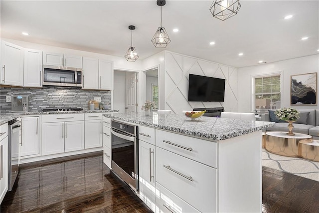 kitchen featuring open floor plan, backsplash, stainless steel appliances, and dark wood-style flooring