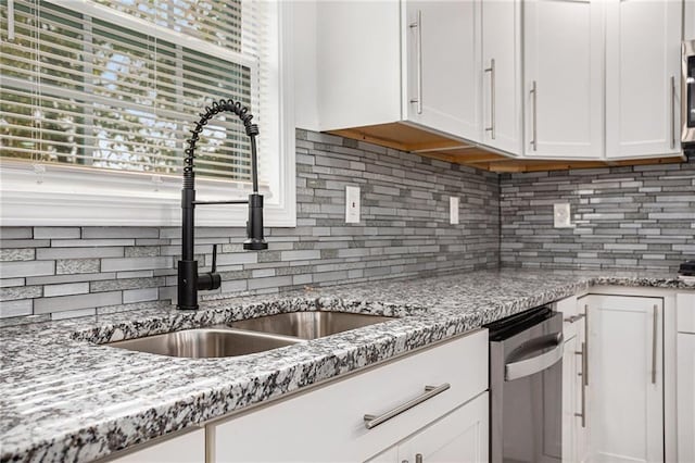 kitchen with tasteful backsplash, appliances with stainless steel finishes, white cabinetry, and a sink